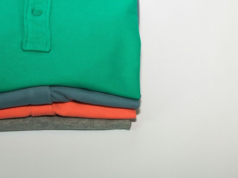 Stack of folded polo shirts in green, blue, coral and grey