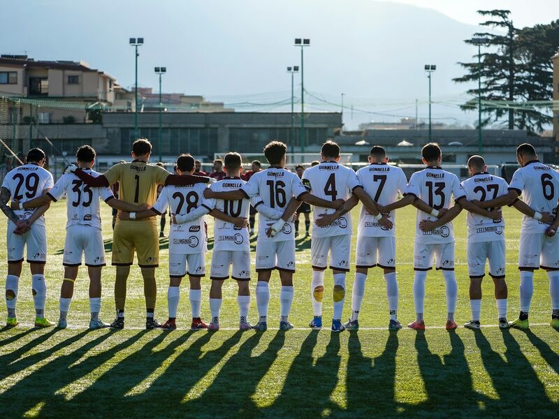 Football team in matching kit with arms around each other